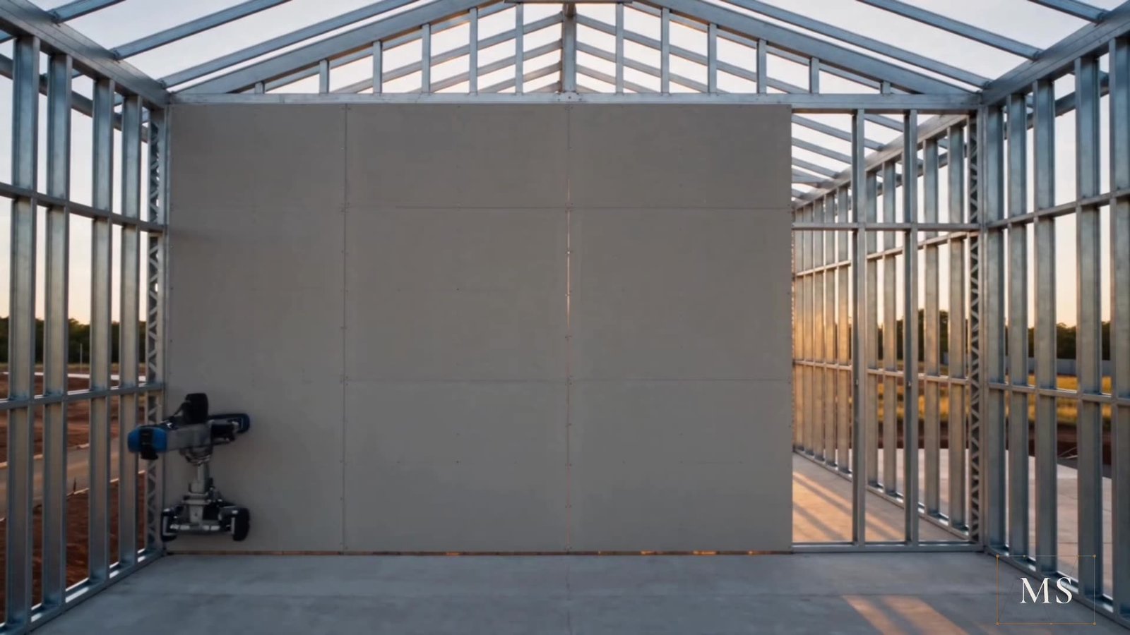 Interior da estrutura em steel frame com o primeiro painel de fechamento instalado, ao pôr do sol.